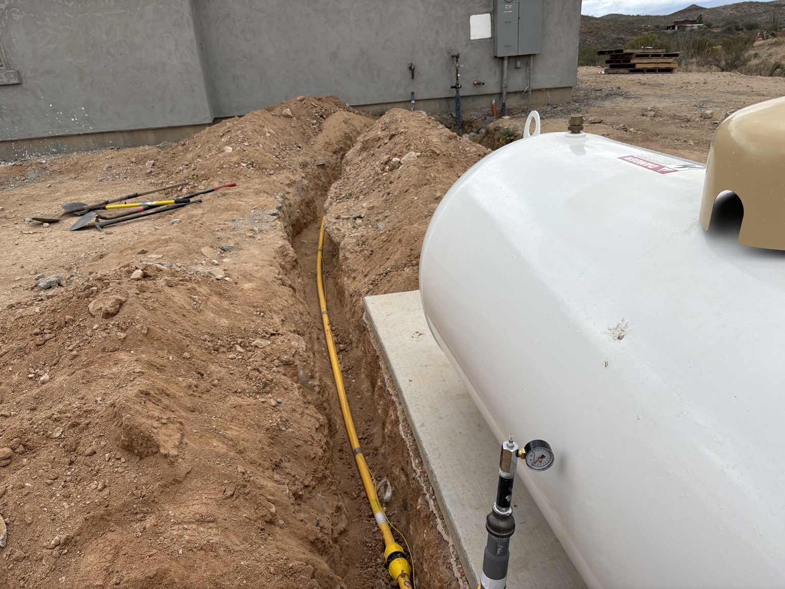 Yellow underground propane gas line installed between a propane tank and building in Southern Arizona