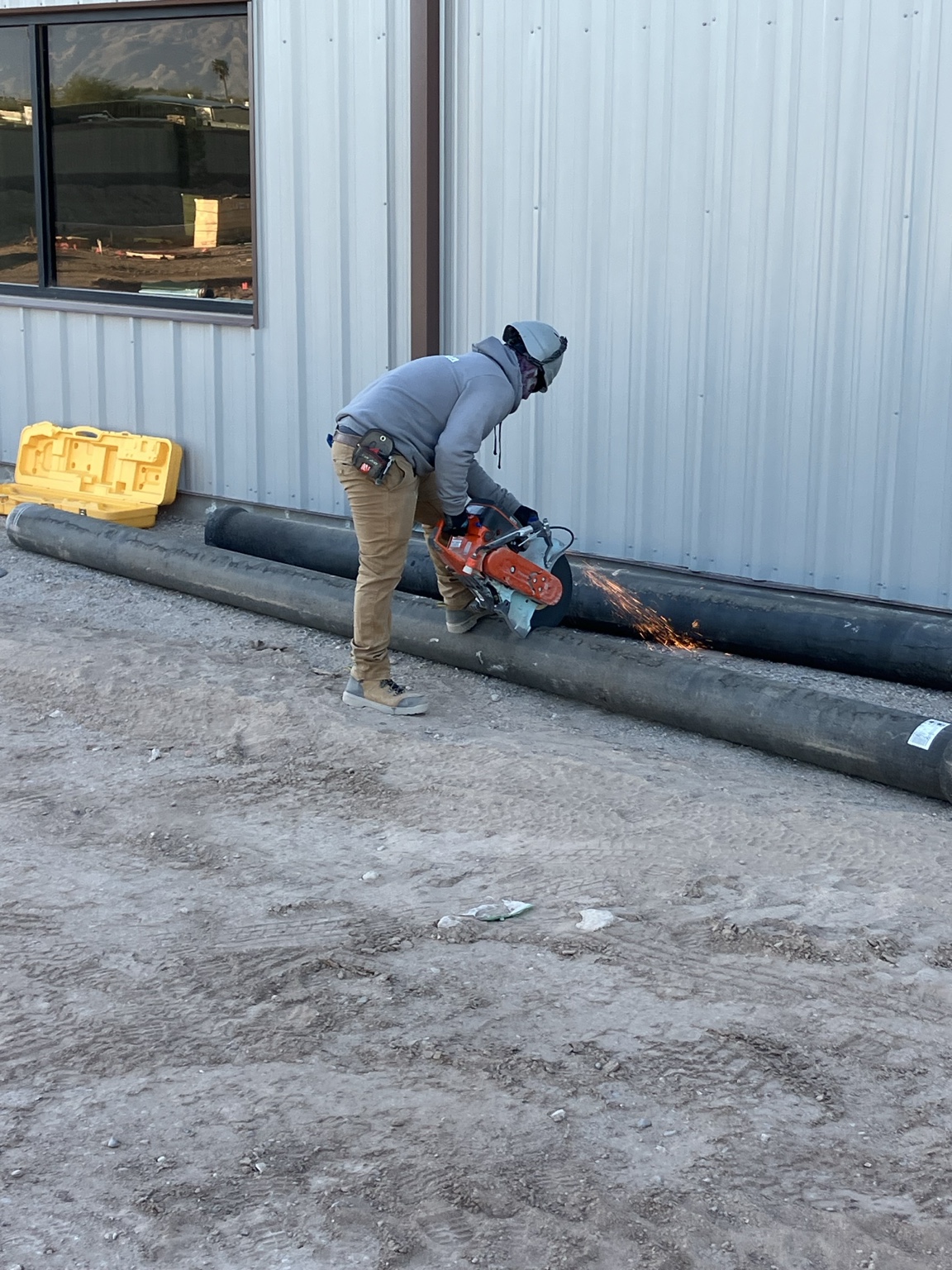 Oasis Plumbing Solutions plumber cutting ductile iron pipe on a commercial jobsite in Tucson